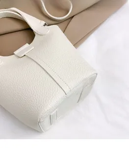 Detailed close-up of white lychee pattern leather on a stylish bucket handbag
