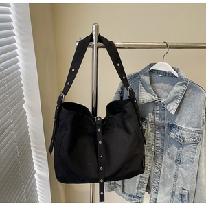 Close-up of black canvas tote bag showing wide adjustable shoulder strap with metal eyelets