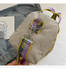 Dettaglio borsa a tracolla beige con tracolla in tessuto colorato e anelli a D in metallo
