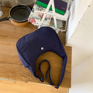 Gros plan du logo rond et de la texture lisse en nylon sur le sac croissant bleu foncé
