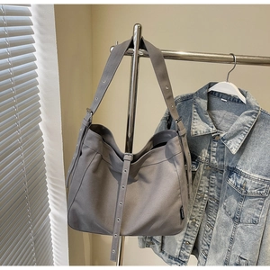 Detail view of a gray canvas tote bag with adjustable metal eyelets and a woven brand label