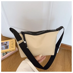 Detail of beige nylon crossbody bag with black lettered strap and decorative zipper