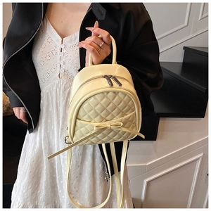 Détail d'un sac à dos matelassé jaune crème avec un nœud élégant et une fermeture éclair