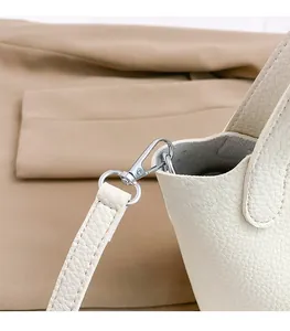 Detail of silver metal clasp on white lychee leather handbag with matching shoulder strap