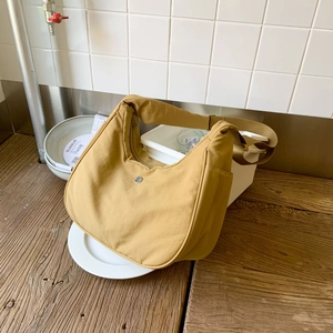 Détail du sac croissant en nylon jaune moutarde montrant la texture et le logo