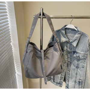Detail view of grey canvas hobo bag with adjustable strap and metallic eyelet decor
