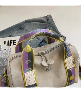 Dettaglio della borsa in nylon beige con manici in jacquard colorato e doppia zip tonda