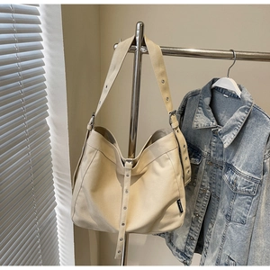 Detail of canvas tote bag showing silver metal eyelets on the shoulder strap and beige fabric