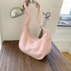 Détail du sac hobo croissant en nylon rose clair avec fermeture éclair et logo sur bois