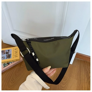 Detail of army green nylon dumpling bag with logo strap and woven rope zipper pull