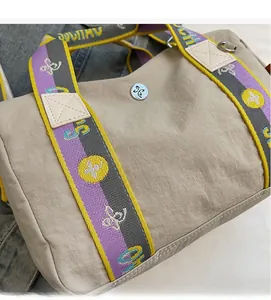 Dettaglio borsa beige a coulisse con spalline colorate a fantasia e logo argento