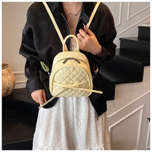 Détail d'un mini sac à dos matelassé avec décoration de nœud et fermeture zippée métal