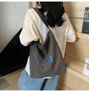 Dettaglio della borsa tote in tela marrone scuro con ricamo TELN! blu in stile a spalla