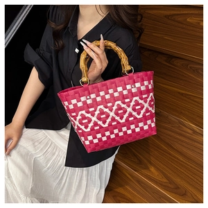 Détail du sac cabas tressé rose rouge avec poignées en bambou et motifs de losanges