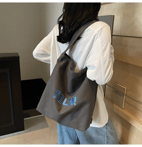Dettaglio della borsa tote in tela grigio scuro con ricamo blu TELN! e tracolla larga