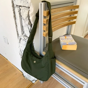 Détail du sac demi-lune en nylon vert olive avec bandoulière réglable et logo en métal