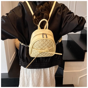 Détail du mini sac à dos matelassé jaune clair avec nœud porté par un mannequin en escalier