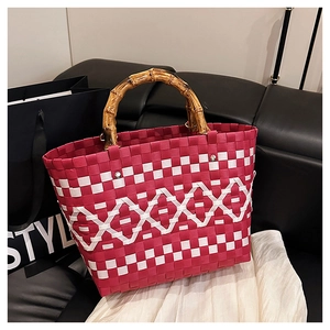 Détail d'un sac cabas tissé rouge et blanc avec des poignées en bambou naturel en U