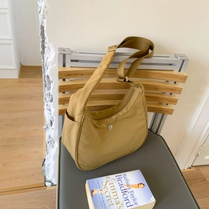 Détail du sac demi-lune en nylon kaki avec bandoulière réglable sur une chaise