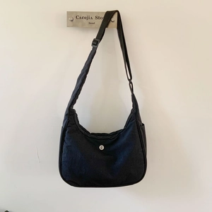 Vue détaillée du sac demi-lune en nylon noir avec bandoulière réglable et logo