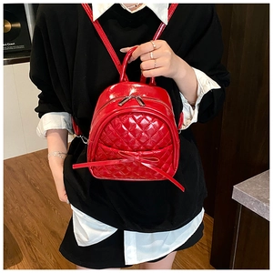 Détail d'un mini sac à dos rouge matelassé avec nœud et fermetures éclair argentées