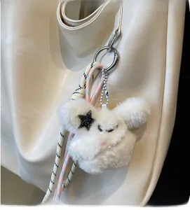 Détail d'un pendentif en peluche blanche avec étoile en paillettes sur un sac