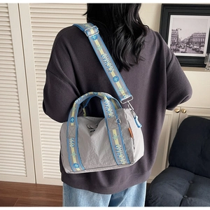 Dettaglio della borsa in nylon grigio con tracolla jacquard colorata ed etichetta