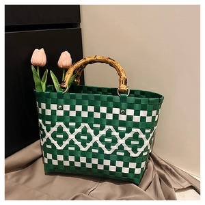 Détail du sac tressé vert et blanc avec poignées en bambou et texture en treillis