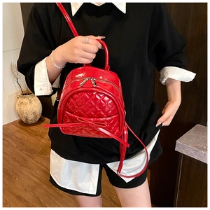 Gros plan d'un sac à dos en cuir verni rouge avec motif matelassé et petit nœud