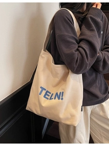 Grande borsa tote in tela beige con ricamo blu indossata per uno stile casual quotidiano