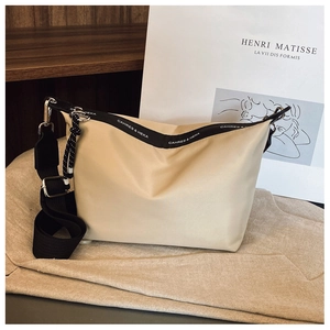 Detailed view of the brand logo on a minimalist beige nylon crossbody dumpling bag