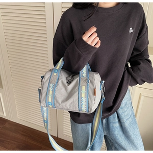 Dettaglio borsa a tracolla in nylon grigio con manici in jacquard colorati e trama impermeabile