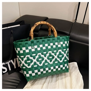 Détail d'un sac à main tressé vert et blanc avec des poignées en bambou rétro