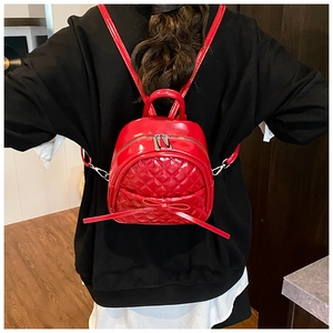 Sac à dos en cuir verni rouge avec motif matelassé et nœud élégant porté par un modèle