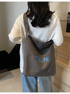 Grande borsa tote in tela grigio scuro con ricamo blu indossata da una modella