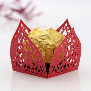Macro detail of laser-cut red paper candy holder with floral lace for party favors