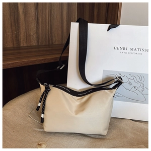 Detail of cream nylon crossbody bag with branded zipper and adjustable black strap
