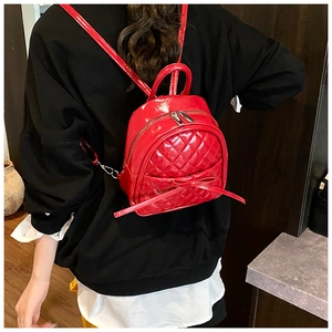 Détail d'un mini sac à dos rouge matelassé avec nœud porté par un mannequin en situation