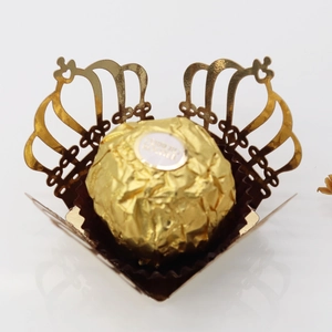 Detail showing a golden laser-cut crown chocolate wrapper with intricate floral patterns