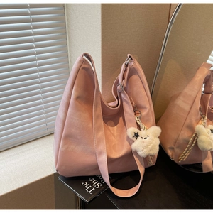 Détail du sac à main en cuir souple rose avec pendentif en peluche et bandoulière