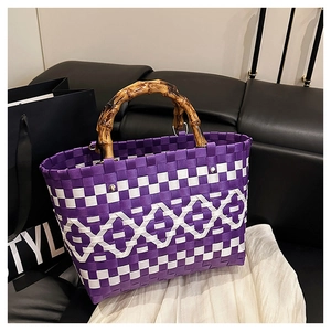 Détail du sac tressé violet avec poignées en bambou et motif géométrique en losange blanc