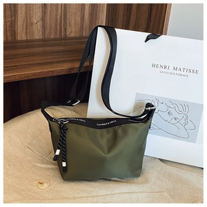 Detailed macro view of olive green nylon crossbody bag with printed strap and zip detail