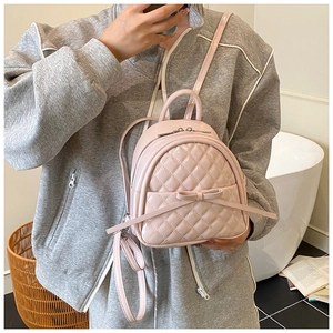 Gros plan du mini sac à dos rose matelassé avec nœud et motif à carreaux sur un modèle