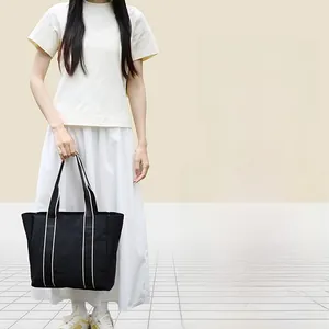 Close-up of durable canvas tote bags in black, brown and grey with striped straps