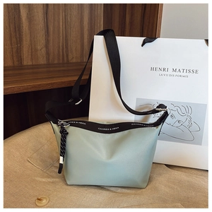Detail of mint green dumpling bag with branded ribbon and wide black nylon strap