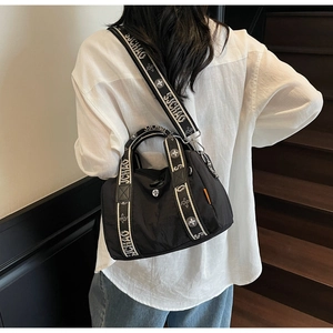 Dettaglio della borsa boston nera con tracolla SJCHAO indossata da una modella in stile casual