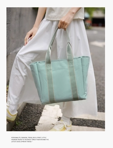 Detail of mint green canvas tote bag with reinforced striped handles and clear fabric texture