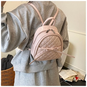 Vue de dos d'un mannequin portant un mini sac à dos rose matelassé avec détail de nœud