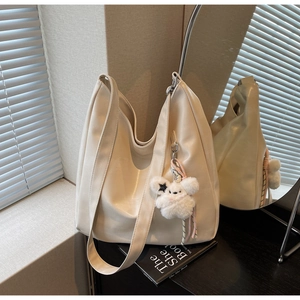Détail d'un grand sac cabas blanc cassé en similicuir avec charm peluche et bandoulière