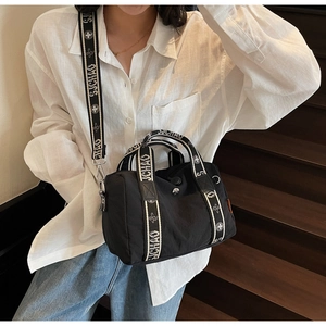 Dettaglio della borsa boston in nylon nero con tracolla larga e manici stampati